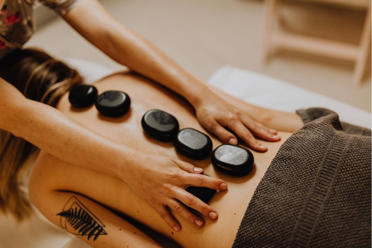 Woman receiving hot stone massage therapy at luxury spa in Boracay with therapist placing heated stones on back
